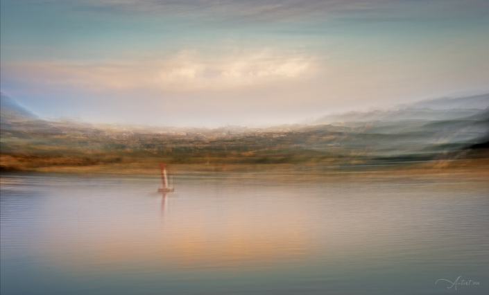 Soft, atmospheric landscape view towards Sedgehill, with distant hills and calm water in the foreground.